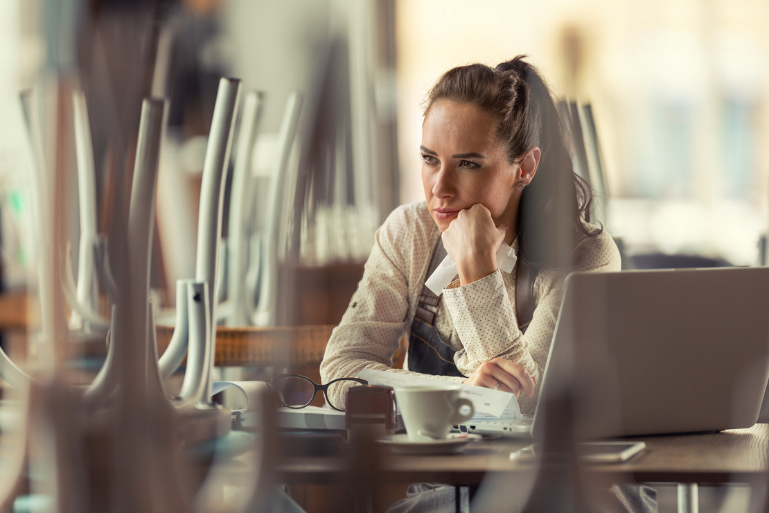 Frau mit Laptop sitzt in geschlossenem Restaurant