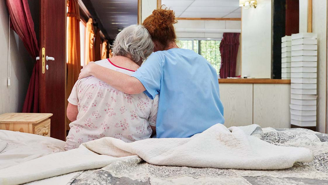 Pflegekraft legt Arm und eine Patientin. 